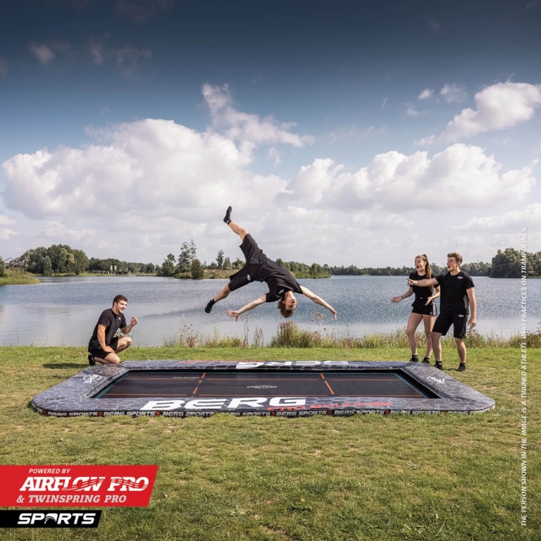 Unge hopper på en BERG FlatGround trampolin ved en sø